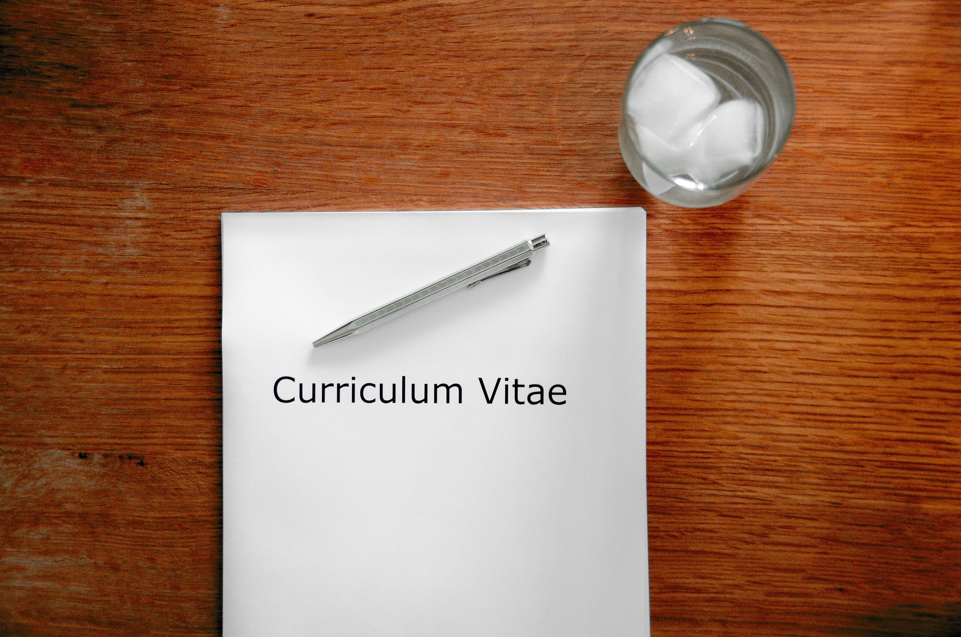 木の机に置かれた「Curriculum Vitae」と書かれた紙とペン